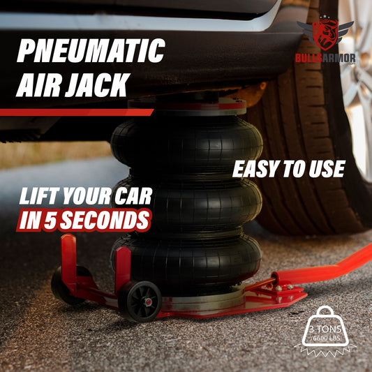 A pneumatic air jack in red color, with triple bag design, lifting a car. The jack is placed on the ground with part of a vehicle wheel visible above it, indicating the jack's use.