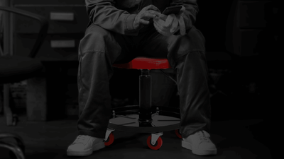 Person sitting on a red and black stool in a workshop setting